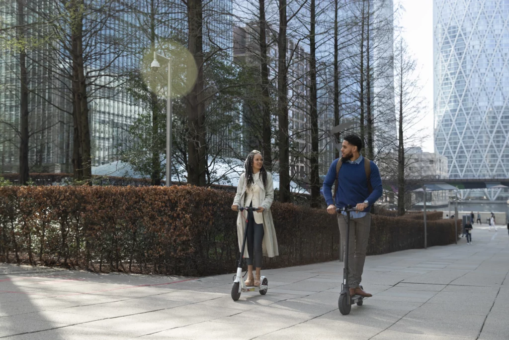 deux personnes vues de face au loin qui circulent dans une grande ville. Des buildings et des arbres sont en arrière plan.